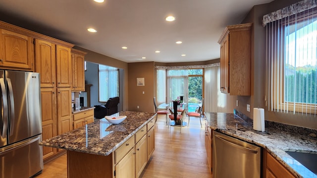 kitchen with light wood finished floors, a kitchen island, dark stone counters, recessed lighting, and stainless steel appliances