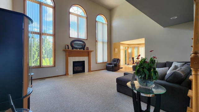 living room featuring a high ceiling, carpet flooring, a fireplace, and baseboards