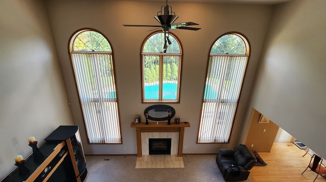 living area with a tiled fireplace, plenty of natural light, a ceiling fan, and baseboards