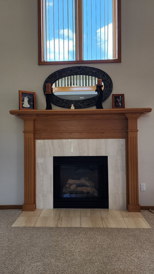 interior details featuring a tiled fireplace, carpet flooring, and baseboards