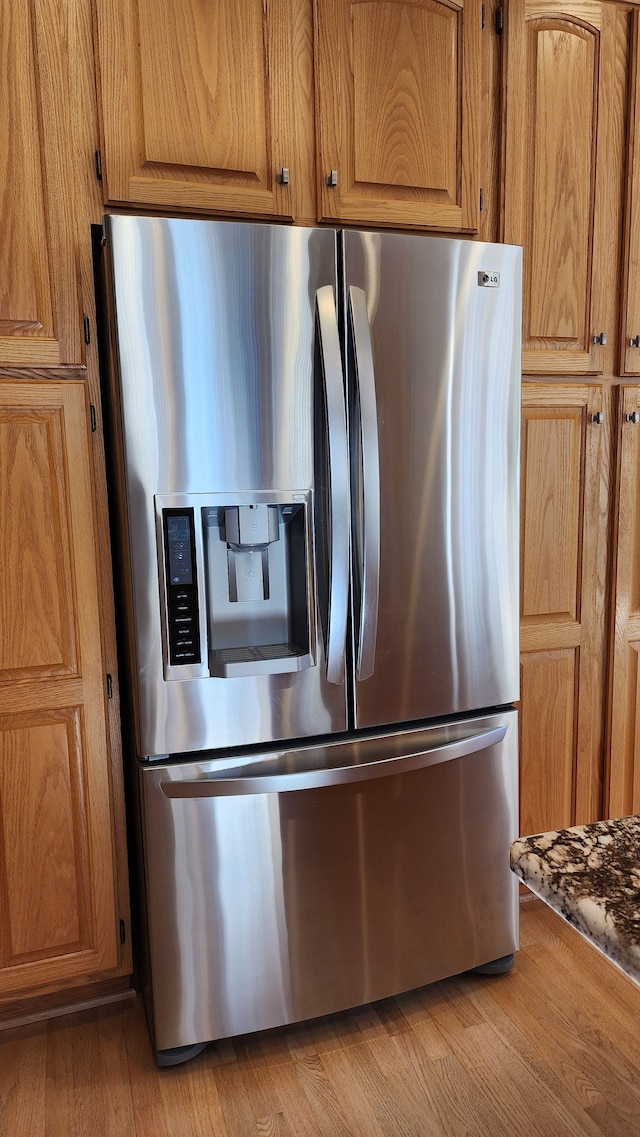 kitchen featuring stainless steel fridge with ice dispenser, light wood-style floors, and brown cabinets