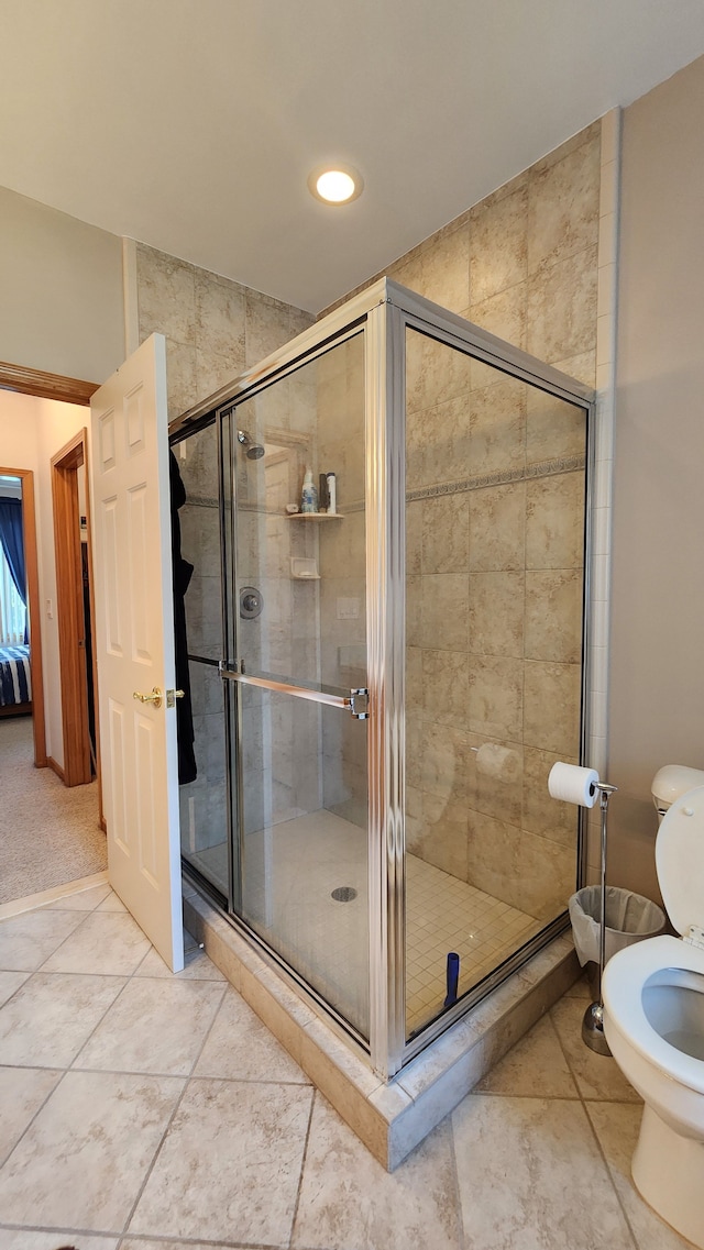 full bath featuring toilet, a stall shower, and tile patterned flooring