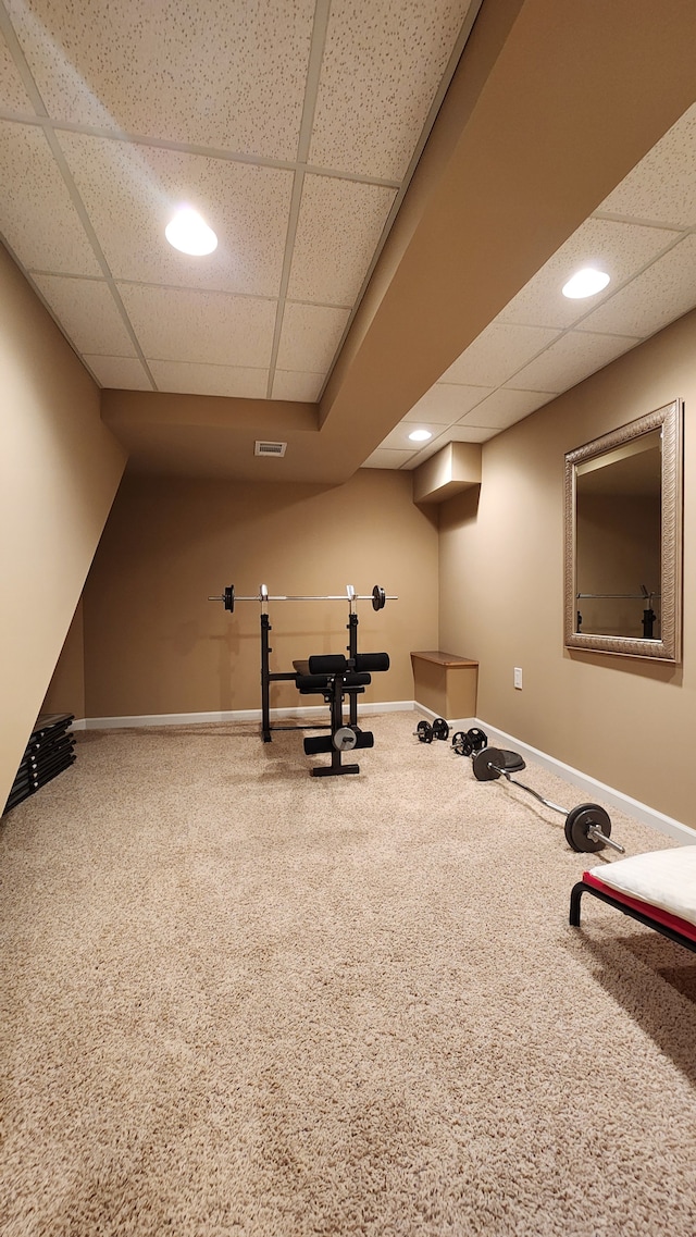 workout area featuring carpet flooring, visible vents, baseboards, and a drop ceiling