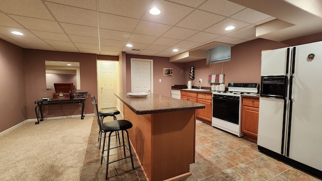 kitchen with a breakfast bar, dark countertops, a center island, white appliances, and baseboards