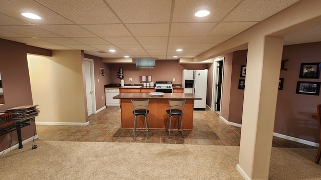 kitchen featuring white appliances, a kitchen island, light carpet, and a breakfast bar