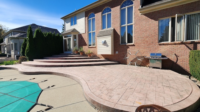 exterior space with brick siding, a swimming pool, a patio area, and entry steps