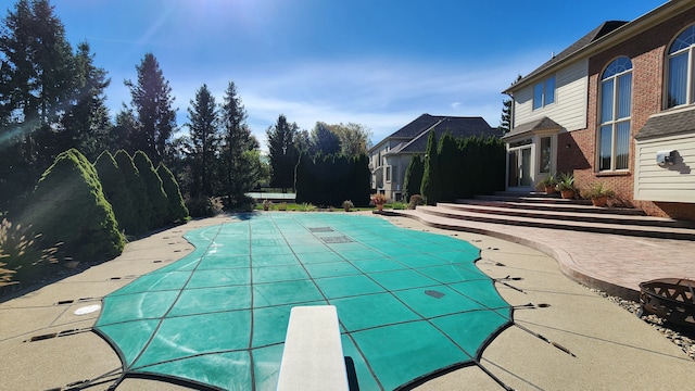 view of pool featuring entry steps, a covered pool, a patio area, and a diving board