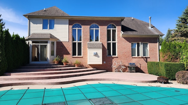 rear view of house featuring a patio, a shingled roof, entry steps, a fire pit, and brick siding