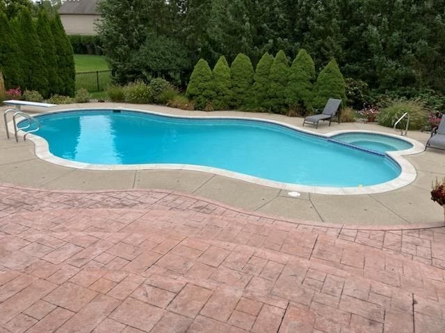 view of pool featuring a patio area, a diving board, a pool with connected hot tub, and fence