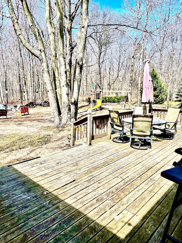 deck with outdoor dining area and a playground