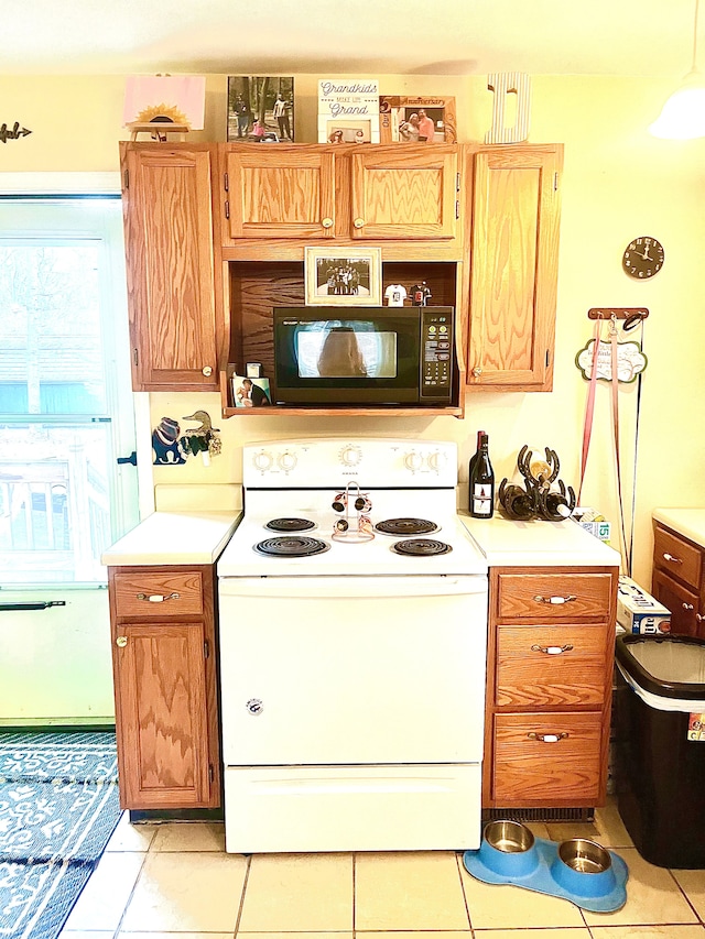 kitchen featuring brown cabinets, white electric stove, light countertops, light tile patterned floors, and black microwave