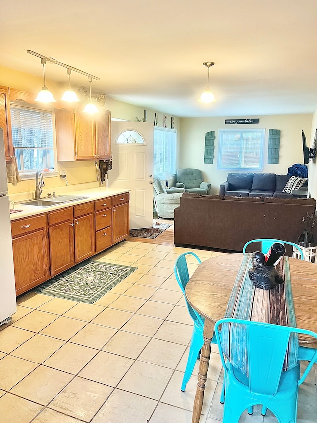 kitchen featuring a sink, brown cabinets, pendant lighting, light countertops, and rail lighting