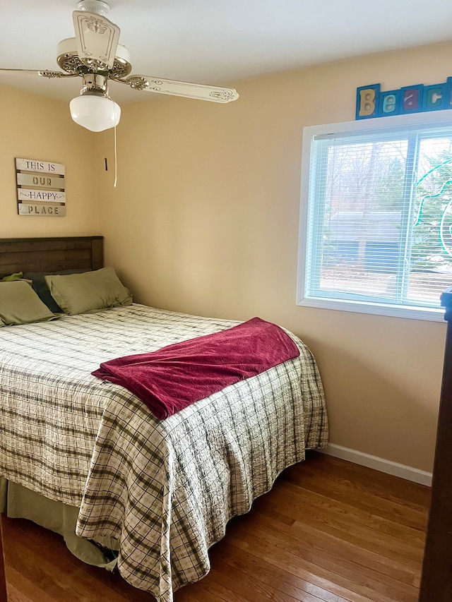 bedroom featuring wood finished floors, baseboards, and multiple windows