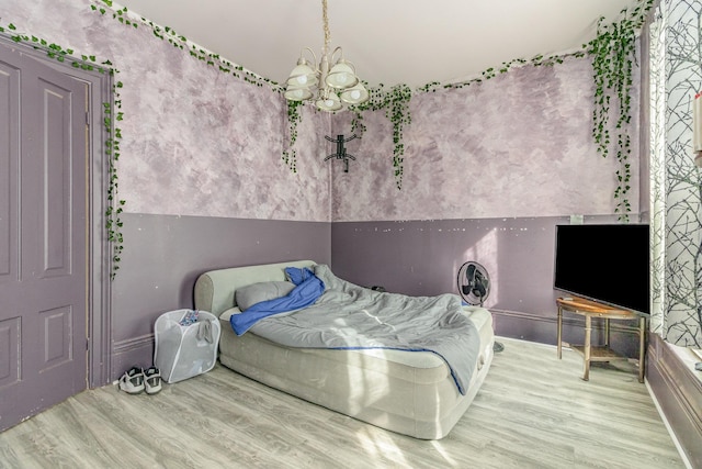 bedroom featuring an inviting chandelier and wood finished floors