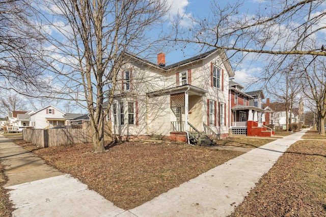 view of side of home featuring a residential view, a chimney, and fence