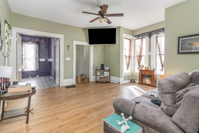 living area with visible vents, baseboards, wood finished floors, and a ceiling fan