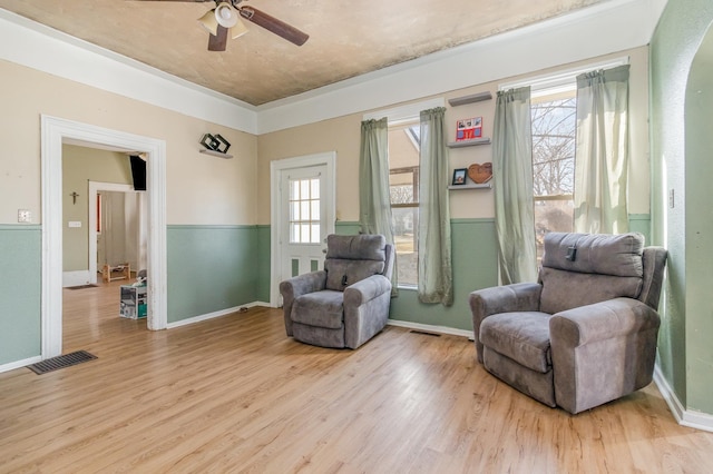 sitting room with light wood-type flooring, a healthy amount of sunlight, a ceiling fan, and visible vents