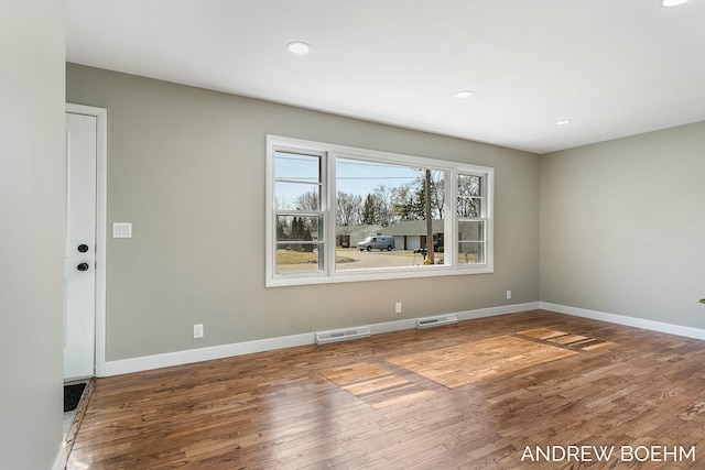 empty room featuring visible vents, wood finished floors, and baseboards