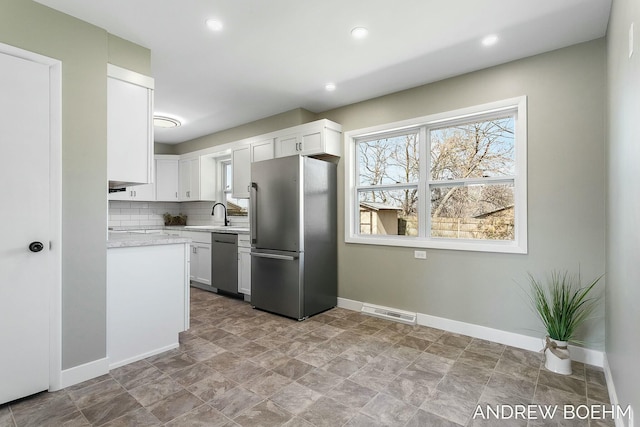 kitchen featuring tasteful backsplash, white cabinets, stainless steel appliances, and baseboards