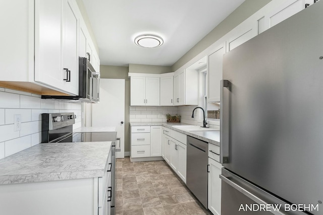 kitchen featuring a sink, appliances with stainless steel finishes, light countertops, and white cabinetry