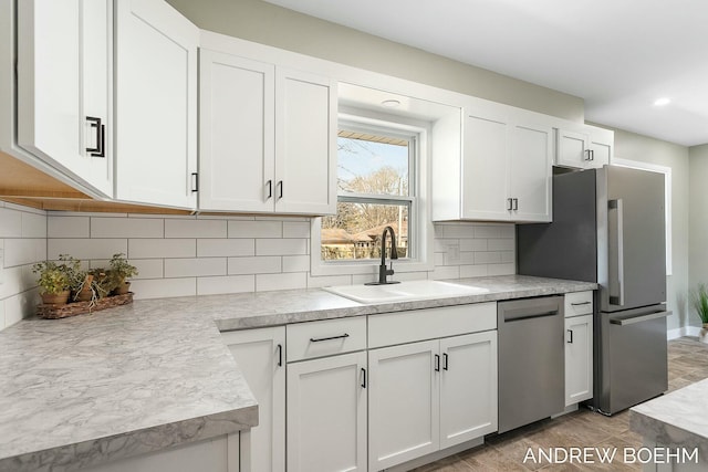 kitchen with a sink, decorative backsplash, light countertops, white cabinets, and stainless steel appliances