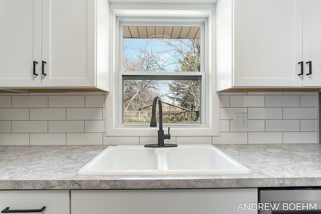 interior details with decorative backsplash, white cabinets, and a sink