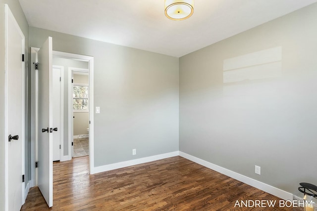 spare room featuring baseboards and dark wood-style floors