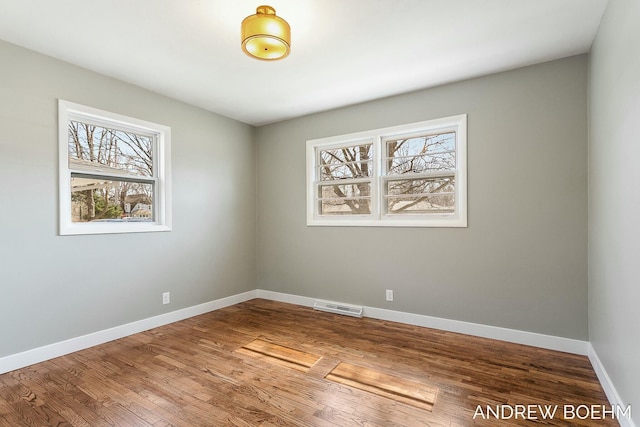 spare room with visible vents, baseboards, and wood finished floors