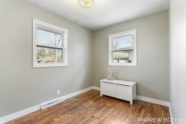 unfurnished room featuring wood finished floors, visible vents, and baseboards