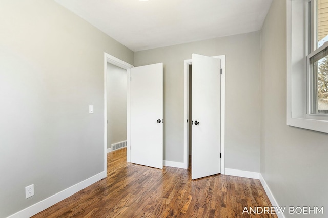 unfurnished bedroom with visible vents, baseboards, and wood finished floors