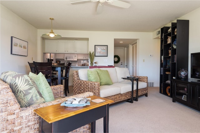 living area with visible vents, light colored carpet, and ceiling fan