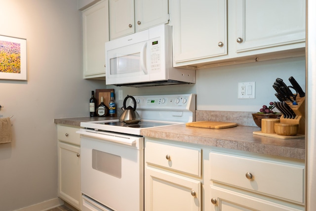 kitchen featuring baseboards, white appliances, and light countertops