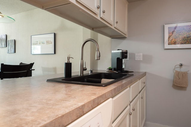 kitchen with a sink, white cabinets, and light countertops