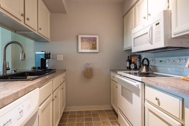 kitchen with a sink, baseboards, white appliances, and light countertops