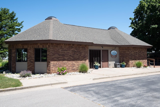 view of front of property featuring brick siding and a shingled roof