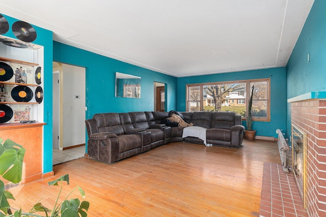 living area with a fireplace, baseboards, and wood finished floors