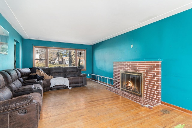 living area featuring baseboards, wood finished floors, and a fireplace