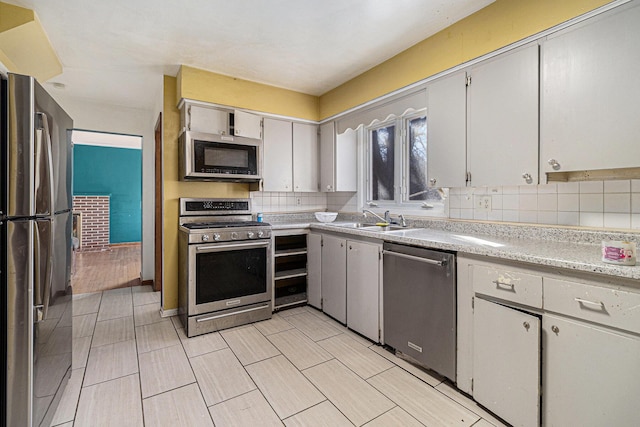 kitchen with wood tiled floor, light countertops, decorative backsplash, stainless steel appliances, and a sink