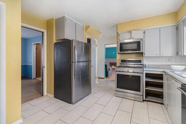 kitchen featuring tasteful backsplash, baseboards, wood finish floors, light countertops, and appliances with stainless steel finishes