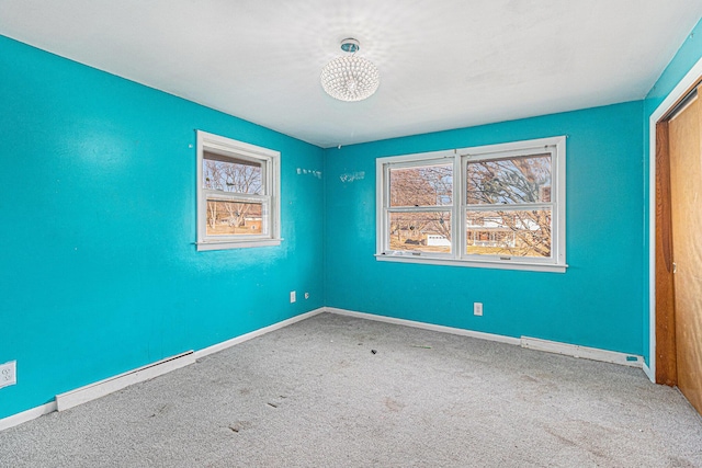 unfurnished room with a baseboard heating unit, carpet flooring, and baseboards