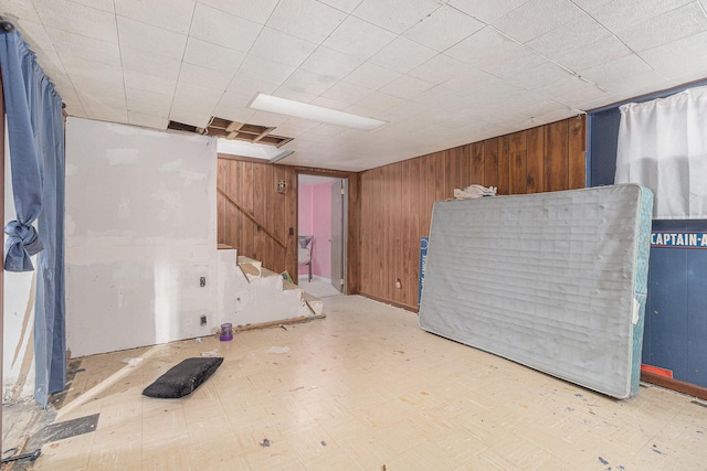 finished basement with tile patterned floors, wooden walls, and stairway