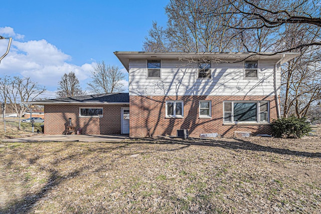 rear view of house with a patio, brick siding, and central AC