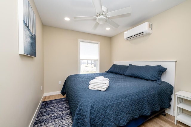 bedroom featuring recessed lighting, baseboards, a wall unit AC, and wood finished floors