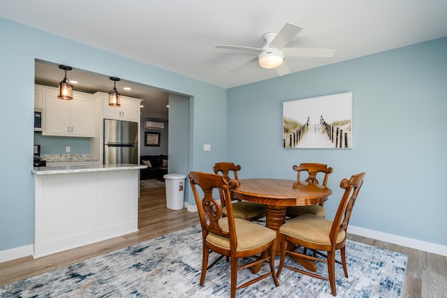 dining area with ceiling fan, baseboards, and light wood-style flooring