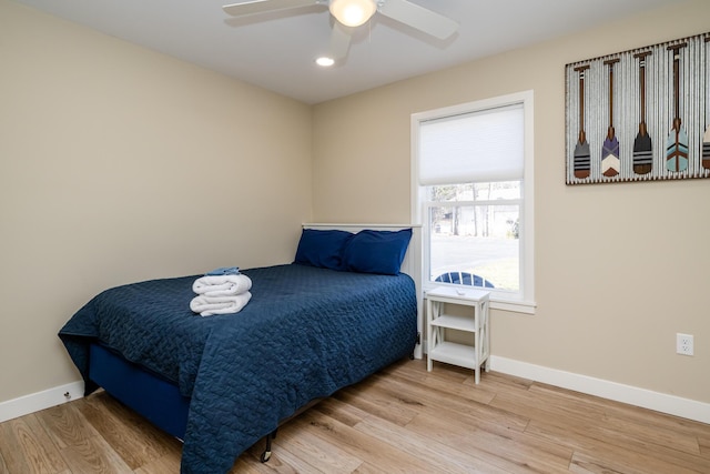 bedroom with a ceiling fan, wood finished floors, and baseboards