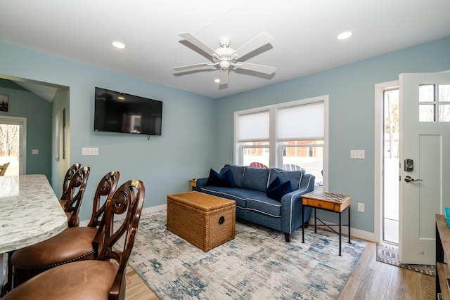 living area with a ceiling fan, wood finished floors, and baseboards