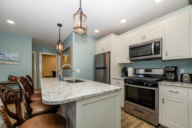 kitchen with a sink, stainless steel appliances, recessed lighting, and white cabinetry