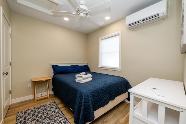 bedroom featuring recessed lighting, light wood-type flooring, baseboards, and a wall mounted AC