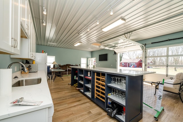 kitchen featuring a sink, open shelves, light wood-type flooring, and white cabinetry