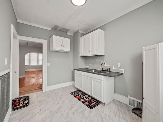 kitchen featuring white cabinetry, visible vents, marble finish floor, and a sink